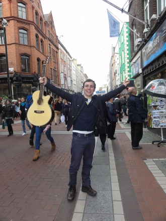 Student holding guitar on city street