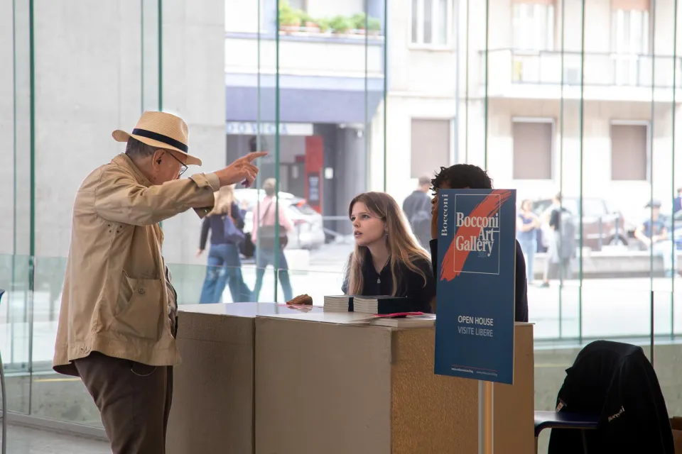 Ragazzi dello staff forniscono indicazioni a un visitatore della Bocconi Art Gallery.