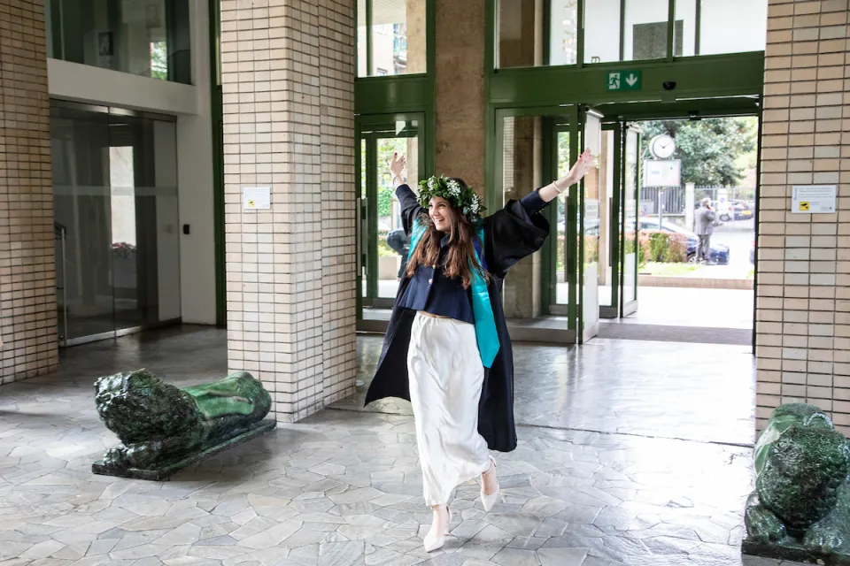 A newly graduated student makes a triumphant entrance in the Sarfatti 25 building.