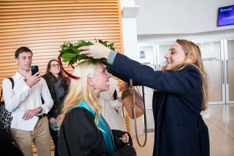 A happy and emotional student gets crowned with laurel by her friend.