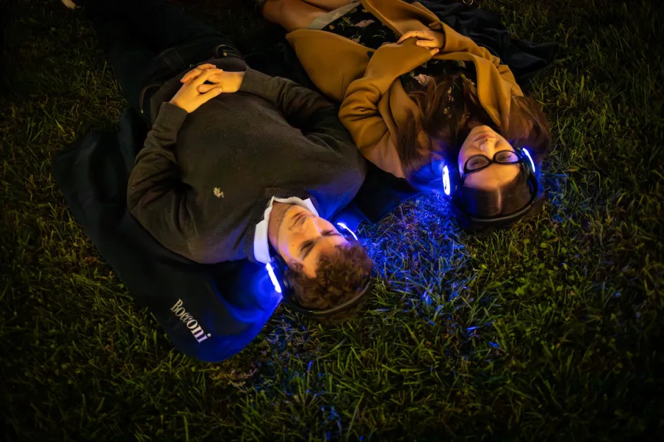 Two students laying down in the new Urban Campus lawns, enjoying the Silent Concert with their eyes closed.