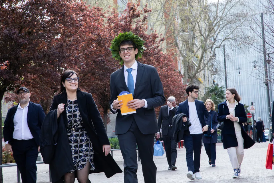 A newly graduated student walks down Piazza Sraffa with his proud mother.