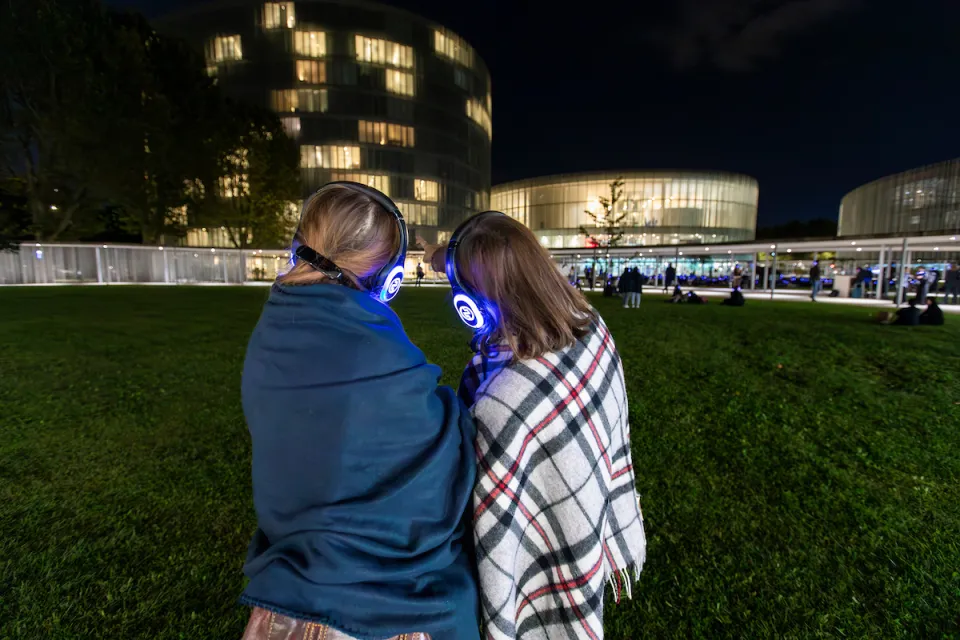 Students with glowing headphones listening to music together during an Isole Sonore event, New Campus Park.