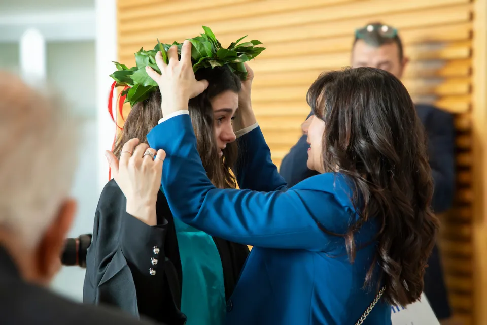 Due amiche commosse: una incorona l'altra dopo la sua laurea.
