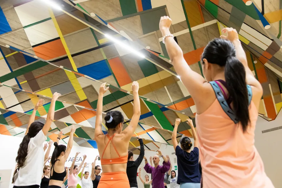 Participants to the Hara Yoga class raise up their arms, following the instructor's directions.