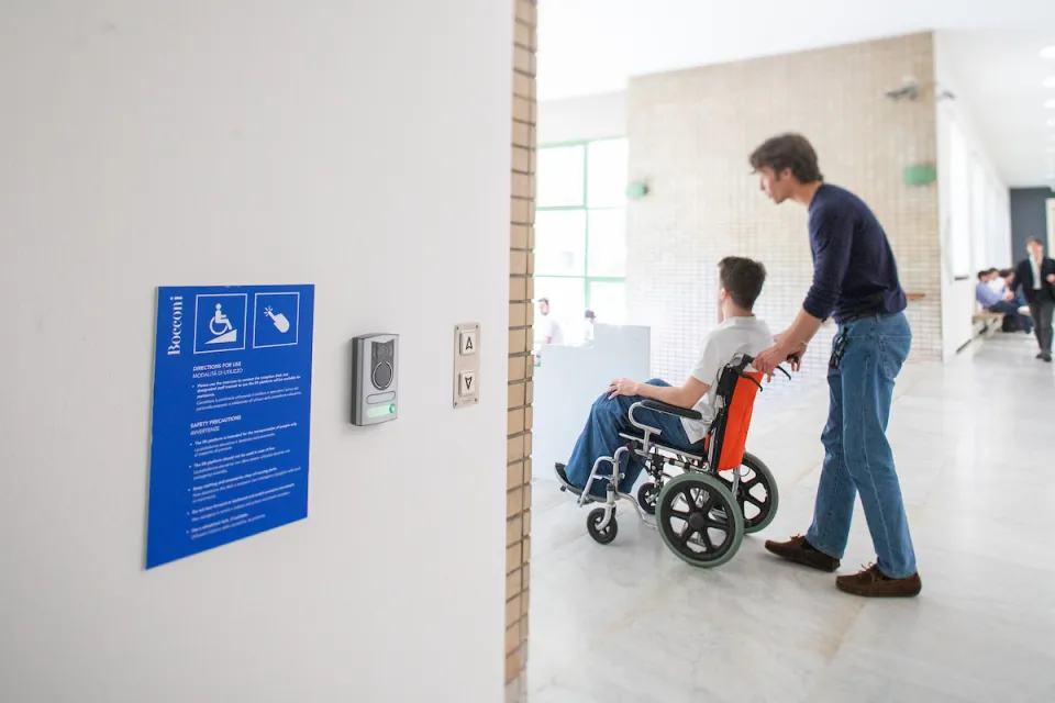 A student in a wheelchair assisted onto the platform built into the stairs at Sarfatti 25.