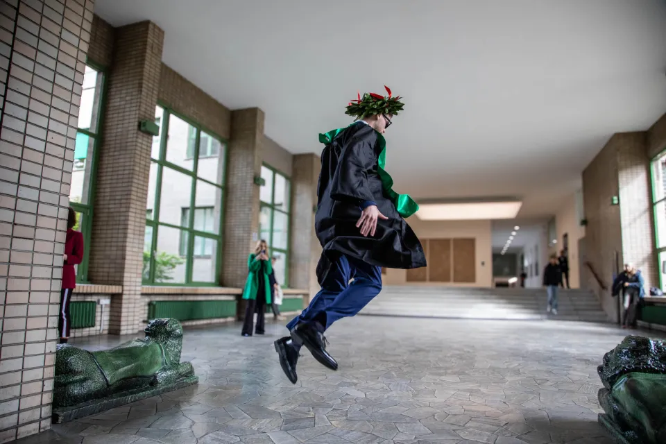 A recent graduate jumps for joy between the lion statues in the Sarfatti 25 building.