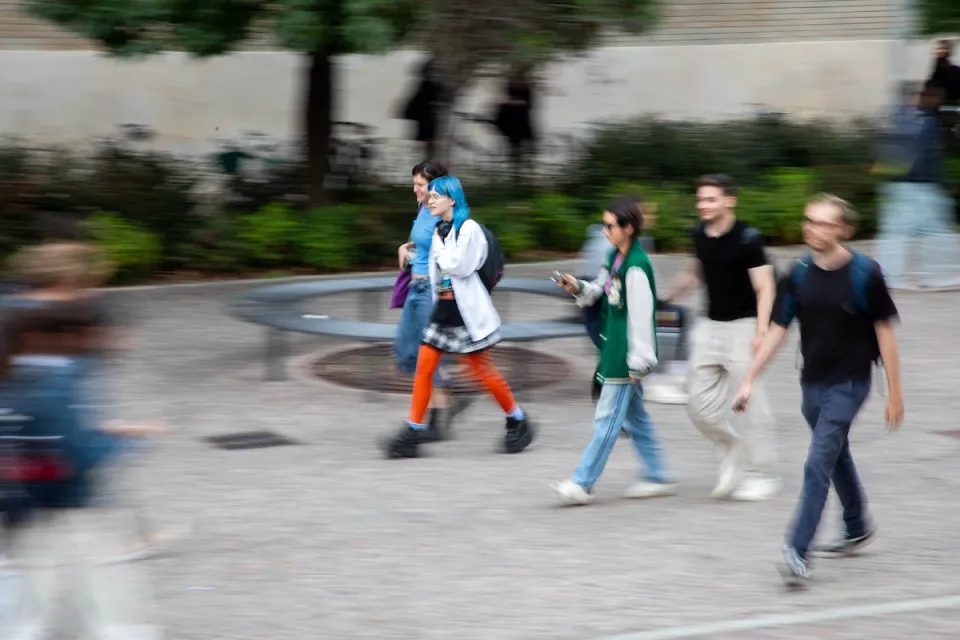 Students in colorful clothes walking between the buildings on Campus.