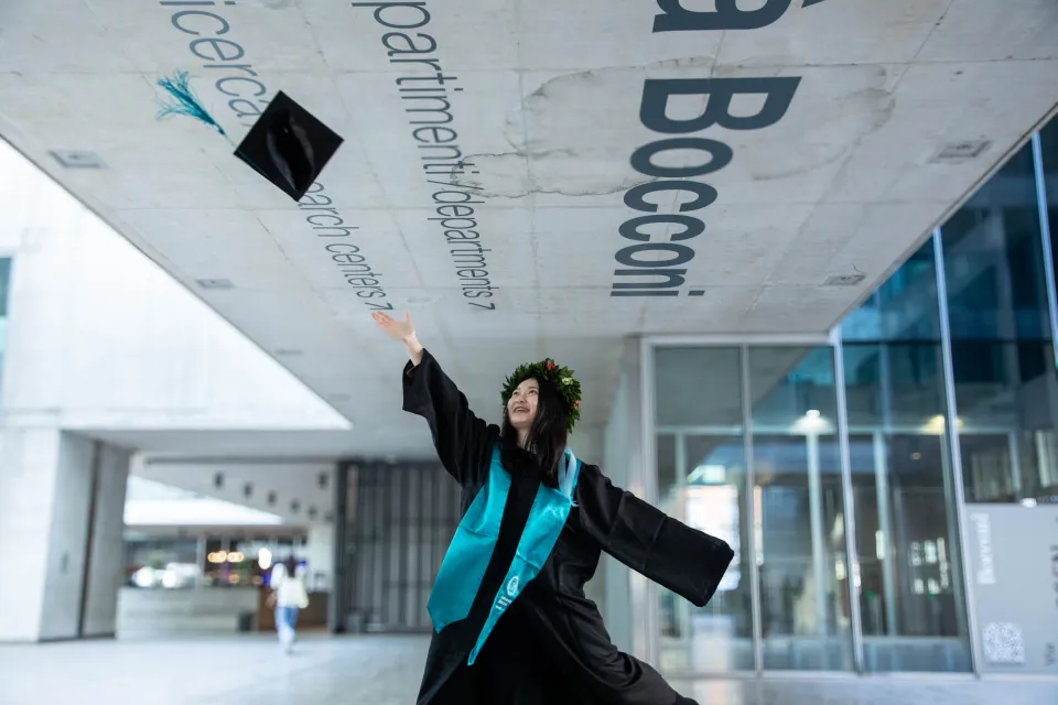 A joyful graduate throws her cap in the Foyer of the Aula Magna.
