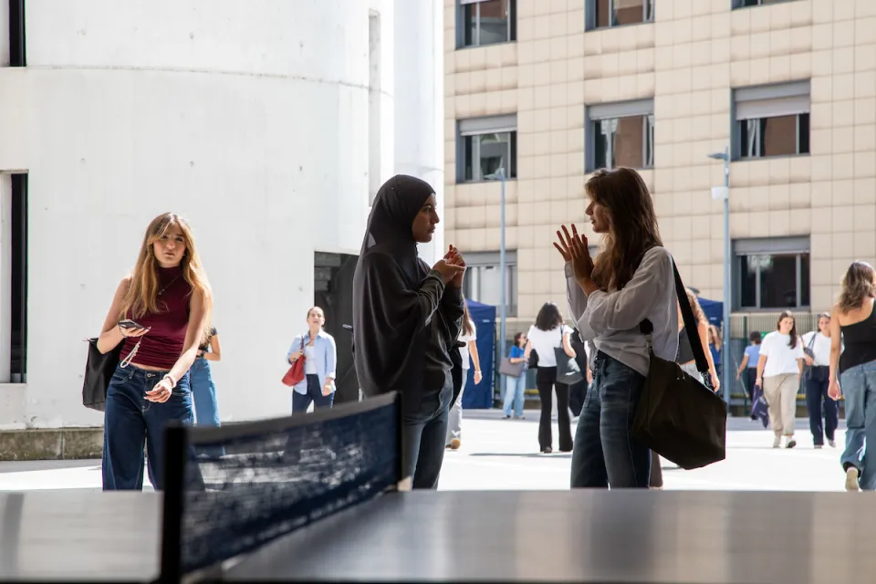 Two students from different cultural backgrounds talking in the Campus Life spaces.