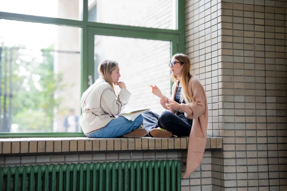 Two students talking in the Sarfatti 25 building.