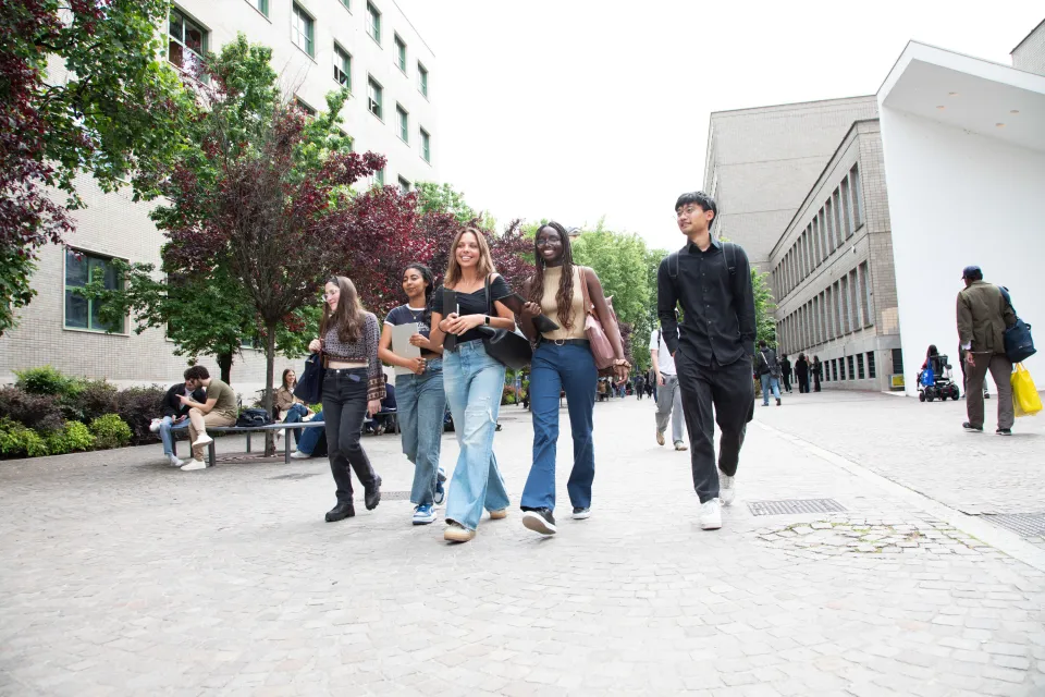 Students from different cultural backgrounds walking in front of the Library.