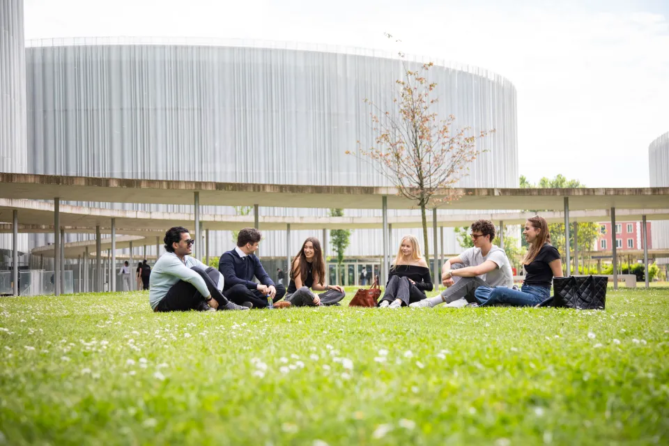 Studenti e studentesse condividono il relax sul prato del nuovo campus urbano.