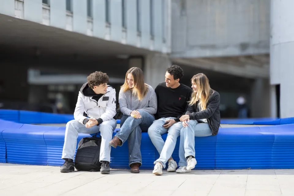 studenti chiacchierano seduti sulla panchina blu realizzata realizzata con cestini di plastica riciclati.