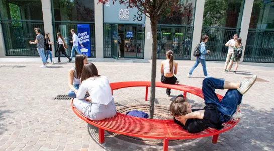 Students sitting on red bench on campus