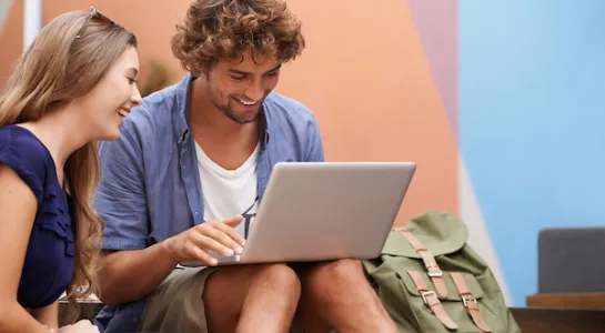 two students holding a laptop